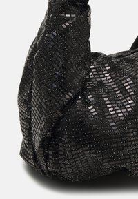 Svart veske med en teksturert overflate dekket av små firkantede paljetter, som skaper et reflekterende mønster. Myk, fleksibel form med en samlet design.