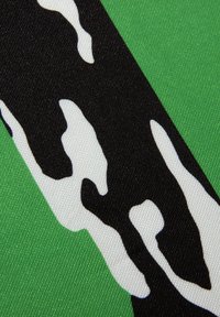Groene stof met een zwart-wit abstract patroon. De textuur lijkt glad, met een lichte glans en zonder zichtbare hardware.