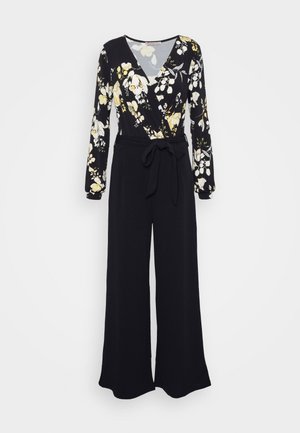 Macacão preto com estampado floral, mangas longas, design envolvente, decote em V e cintura com laço. Apresenta uma silhueta larga e fluida com detalhes em flores amarelas e brancas.