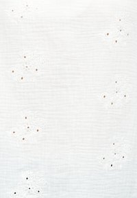 Tissu blanc texturé avec des motifs floraux brodés subtils et de petits trous répartis régulièrement sur la surface.