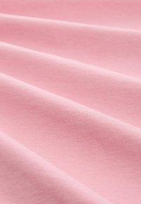 Tela de color rosa claro con una textura suave, que presenta líneas horizontales sutiles y pliegues suaves, indicando un material blando y elástico.