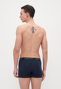 Sötétkék boxer alsónadrág fekete derékkal, amelyen a "COPENHAGEN STUDIOS" logó látható; sima anyag, slim fit kialakítás, és nincsenek látható minták.