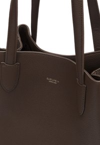 Brown leather tote bag with textured surface, top handles, and embossed brand logo in gold. Open design for easy access.