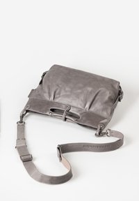 Grijze leren schoudertas met een zachte textuur, opvouwbare klep en verstelbare schouderband met gesp. Bevat uitsneden op de voorkant.