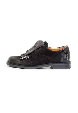 Chaussure habillée en cuir noir avec une large couverture des lacets sécurisée par deux fermetures éclair et un petit porte-clés en métal attaché au talon.