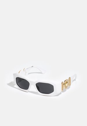 Occhiali da sole bianchi con montatura angolare, lenti nere e accenti in medaglione dorato sulle tempie. Realizzati in plastica con una texture liscia.