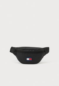 Zwarte heuptas gemaakt van duurzaam stof, met een voorvak met ritssluiting en een klein rechthoekig logoplaatje in rood, wit en blauw.