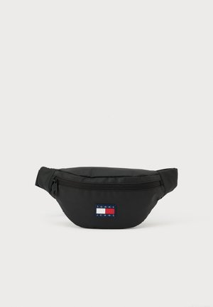 Zwarte heuptas gemaakt van duurzaam stof, met een voorvak met ritssluiting en een klein rechthoekig logoplaatje in rood, wit en blauw.