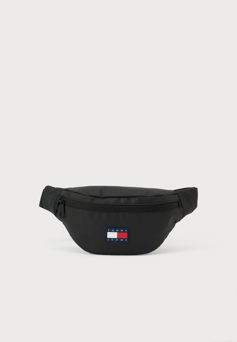 Zwarte heuptas gemaakt van duurzaam stof, met een voorvak met ritssluiting en een klein rechthoekig logoplaatje in rood, wit en blauw.