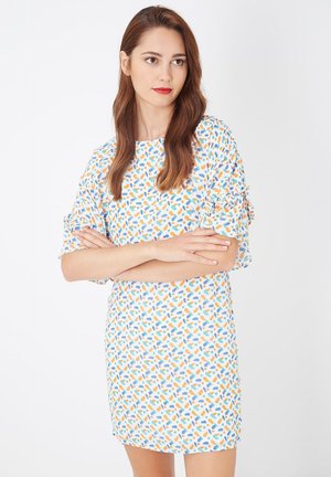 Vestido de manga corta con una base blanca y un vibrante patrón disperso de formas naranjas y azules. Tejido suave con un corte holgado.