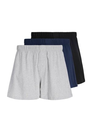 Ung mand med kort blondt hår iført lysegrå bomuldsboxershorts, stående mod en ensfarvet hvid baggrund.