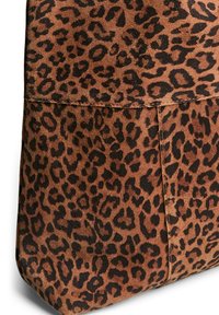 Sac en daim marron ornée d'un motif de léopard noir, avec une texture lisse et des détails de couture subtils le long des coutures.