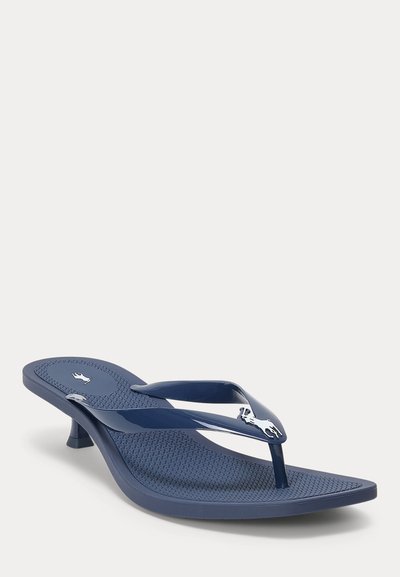 Marineblå hælsandal med tynn stropp, teksturert fotsåle og sølv hestelogo på glinsende stropper, vist på hvit bakgrunn.