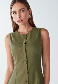 Abito senza maniche color verde oliva con scollatura rotonda, caratterizzato da cinque bottoni abbinati sul davanti e una superficie del tessuto liscia.
