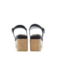 Sandalias de plataforma de cuero negro con tacones de corcho, correas de tobillo ajustables y plantillas suaves. Diseño simple con hardware minimalista.