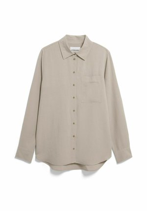 Chemise beige à manches longues avec boutons, col pointu et poche poitrine, posée à plat sur un fond blanc.