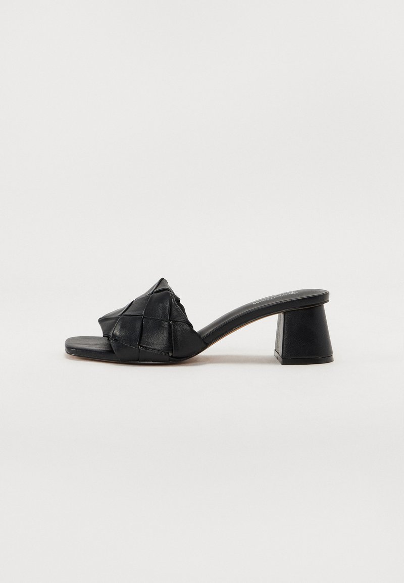 Black leather block-heeled slide sandal featuring a woven upper design and flat sole, with a semi-gloss finish.