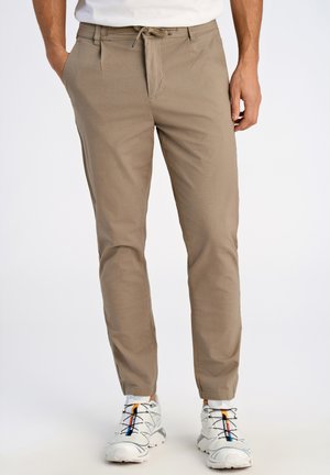 Housut vaaleanbeige sävyssä, nyörikiinnityksellä vyötäröllä, slim fit -mallia, sileä pinta ja sivutaskut, yhdistettynä valkoisiin urheilukenkien, joissa on moniväriset vivahteet.