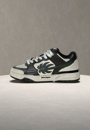 Valget ja musta madala säärega tennisejalanõud tumerohelise palmipuulogo ja "Palm Angels" teksti tallal.