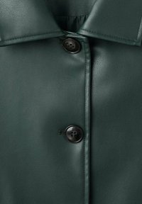 Giacca camicia in ecopelle verde con colletto a punta, chiusure a bottoni e una finitura testurizzata con una delicata lucentezza.