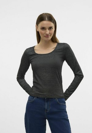 Zwarte top met lange mouwen en een ronde hals, gemaakt van ribstof met een metallic glans, gecombineerd met blauwe jeans. De stof reflecteert subtiel licht.