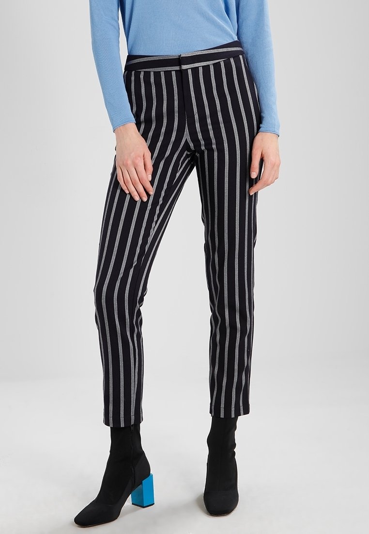 Randy byxor i svart och grått, med en åtsittande design och en slät yta. Sammanvävt med svarta ankelskor med blå blockklackar.