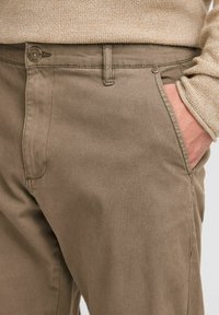 Khaki cotton pants with a smooth texture, featuring front pockets, a button closure, and a single visible pocket detail.
