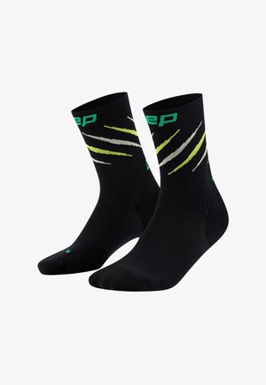Schwarze Sportstrümpfe mit grünen und weißen diagonalen Streifen und Logo; knöchelhoch mit gerippter Textur für zusätzlichen Halt.