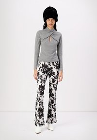 Gray, long-sleeve top with twist detail and keyhole; flared black and white spotted pants; white heeled boots; black fur hat.