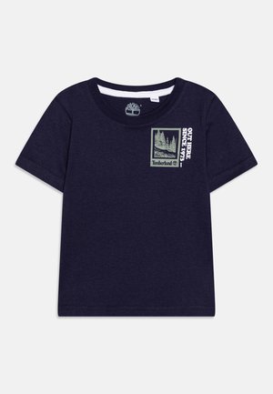 T-shirt bleu marine à manches courtes pour tout-petit avec col rond, logo Timberland et texte « Out Here Since 1973 » à côté d'un graphique d'arbre sur la poitrine.