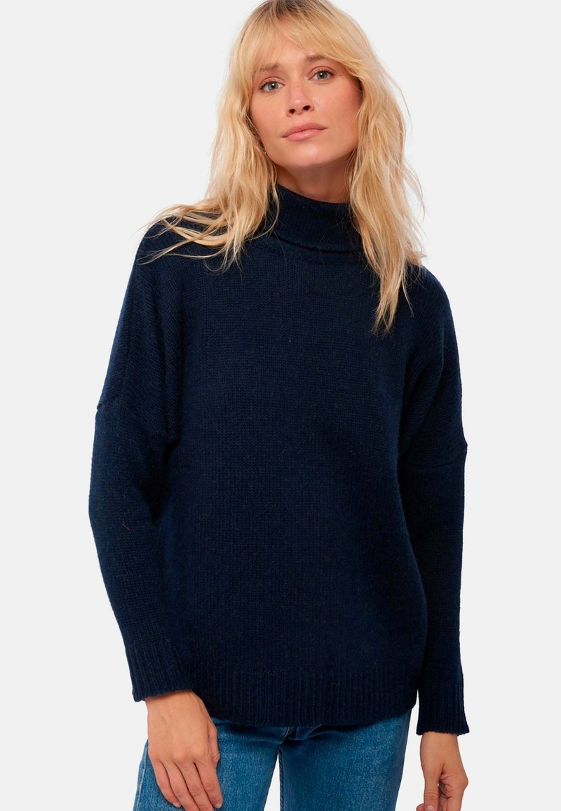 Marineblaues Strickpullover mit hohem Kragen, überschnittenen Schultern und gerippten Bündchen. Weicher Stoff mit oversized Passform.