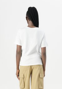 Hvit bomulls T-skjorte med korte ermer, rett snitt og rund hals, kombinert med beige cargo-bukser med sidelommer.