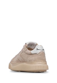 Sneaker in suede beige con suola in gomma texture, punta rotonda e un tallone bianco a contrasto con un accento nero.