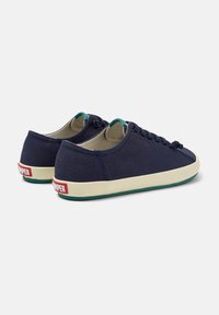 Marineblauwe canvas sneakers met een ronde vorm, witte rubbere zool, teal accenten en rode branding op de hak. Vetersluiting met ronde veters.