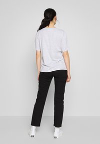 Camiseta gris de manga corta combinada con pantalones negros de pierna recta y zapatillas altas blancas. La tela parece suave y casual.