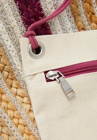 Torba z płótna z bordowym zamkiem błyskawicznym, szarą metalową okuć i plecioną fakturą. Zawiera pleciony różowy sznurek i przelotkę do zamknięcia.