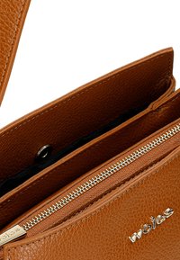 Borsa a mano in pelle marrone con finitura testurizzata, dotata di chiusura a zip, chiusura magnetica e fodera interna nera. Logo impresso sulla parte anteriore.