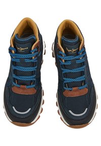 Zapatillas de Navy con acentos en azul y marrón, que presentan una tela texturizada, cordones redondos y una suela de goma gruesa. Logo visible en la lengüeta.