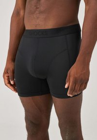 Boxer shorts in cotone nero con una vestibilità aderente, vita elastica con il marchio "SNOCKS" e una texture liscia con dettagli di cucitura minimi.