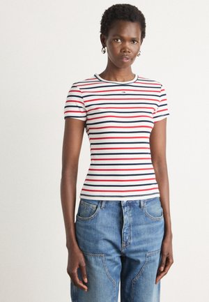 Pasiasty t-shirt z krótkim rękawem w kolorach białym, czerwonym i granatowym. Fason dopasowany z ribbowanym okrągłym dekoltem i wyszywaną aplikacją na piersi. Na zdjęciu przedstawione dżinsy.