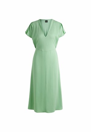 Zielona sukienka uszyta z gładkiego materiału, z dekoltem w serek, krótkimi falbanami oraz dopasowanym talią, która rozszerza się na dole.