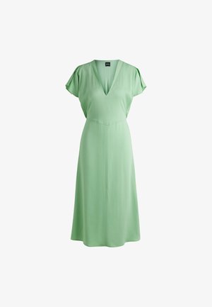 Zielona sukienka uszyta z gładkiego materiału, z dekoltem w serek, krótkimi falbanami oraz dopasowanym talią, która rozszerza się na dole.