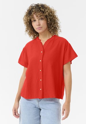 Red short-sleeve shirt with a scalloped collar, button front, and textured fabric. Features decorative stitching along the neckline.