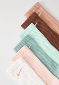 Set aus sechs gerippten Socken in Pastellfarben: Weiß, Pfirsich, Mintgrün, Hellgrün, Braun und Orange. Jede Socke trägt ein Nike-Logo.