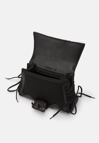 Bolsa preta com uma mistura de pele lisa e malha texturizada, com uma forma arredondada, rendas nas laterais e fecho de fecho.