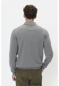 Grå tröja med långa ärmar och polokrage, med en slät textur och åtsittande design, sedd bakifrån.