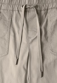 Ljusbeige shorts med dragsnöre som har resårmidja, två framfickor och dragkedjor med metalldetaljer. Mjuk, vävd tygstruktur.