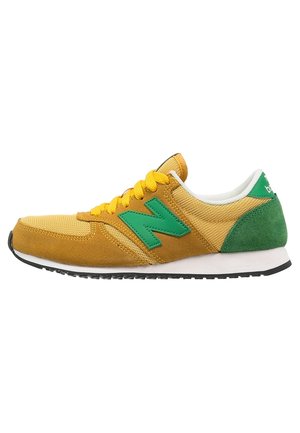 Gule og grønne snørebåndssneakers med ruskind og mesh-overdel, grøn "N"-logo på siden, hvid mellemsål og sort ydersål.