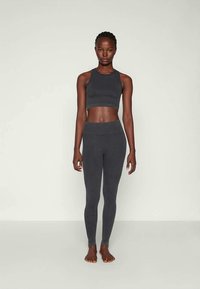 Conjunto atlético gris de canalé que incluye un top corto y leggings de cintura alta. La tela es suave, con un ajuste ceñido y costuras mínimas.