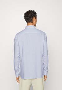 Randig långärmad skjorta i ljusblått och vitt. Har en spetsig krage och knäppningar vid ärmsluten. Mjuk tyg med en normal passform.